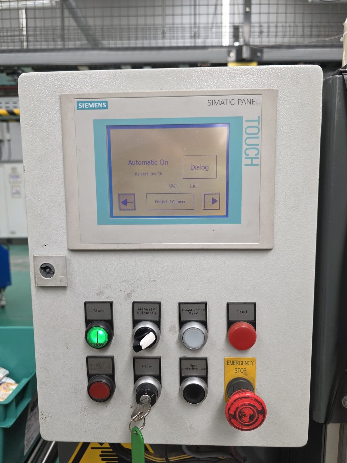 Original Siemens TP177A SIMATIC touch panel on the AMI lidding machine showing a basic interface with Dialog and Lid buttons, alongside physical controls including emergency stop, fault indicator, manual/automatic selector, and start/stop buttons