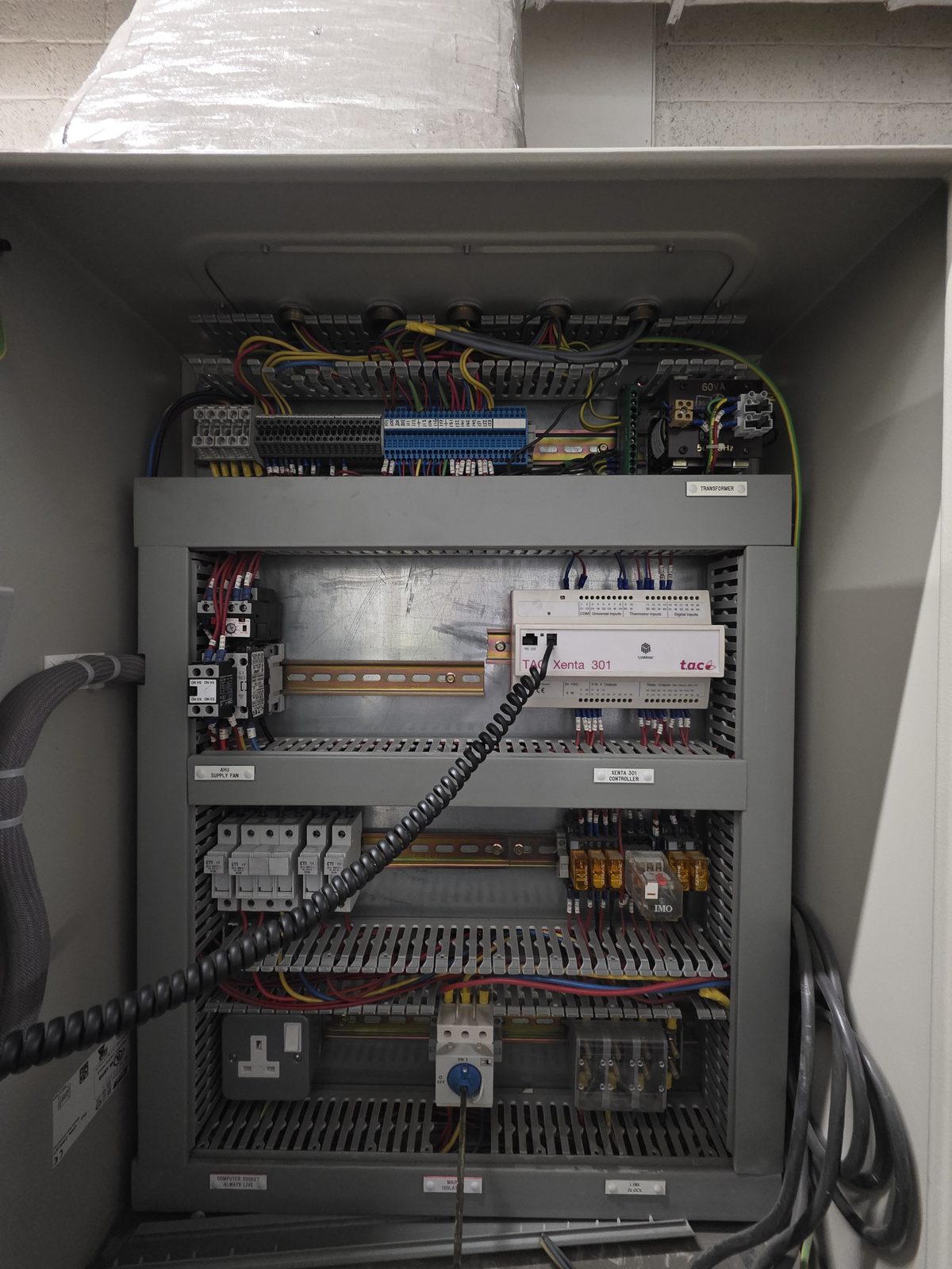 Inside the AHU control panel showing the TAC Xenta 301 DDC controller mounted on DIN rail, surrounded by terminal blocks, relays, transformer, and field wiring