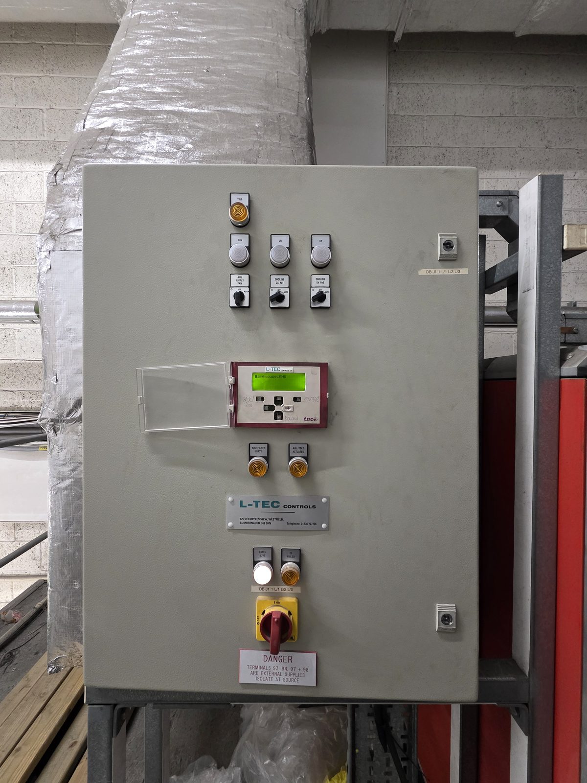 AHU control panel with TAC Xenta OP operator display showing live values, L-TEC Controls label plate, selector switches, indicator lamps, and rotary isolator switch
